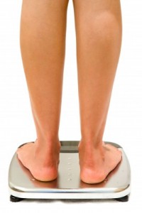 woman-stands-on-weighing-scales-isolated-on-white